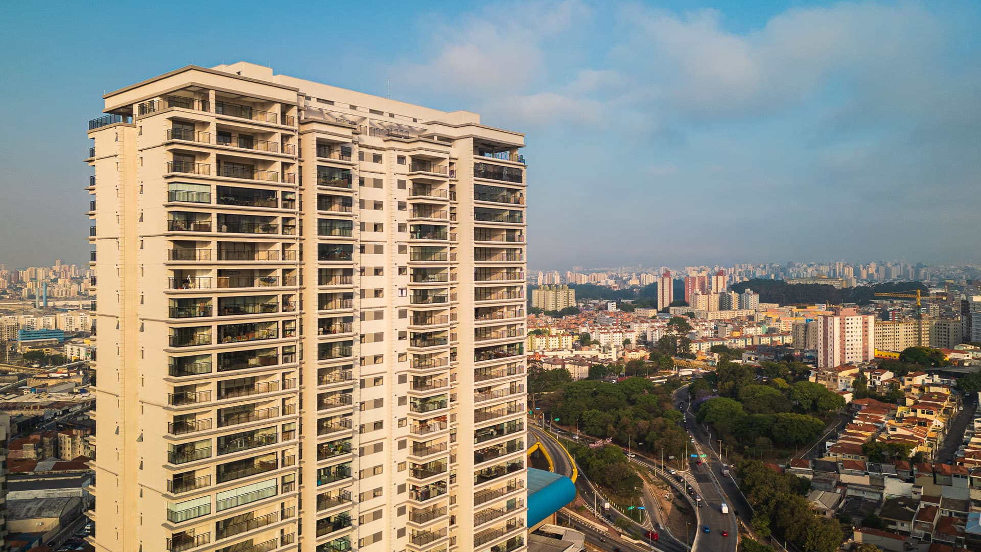 Vista aérea da fachada lateral de prédio residencial alto com varandas e entorno urbano